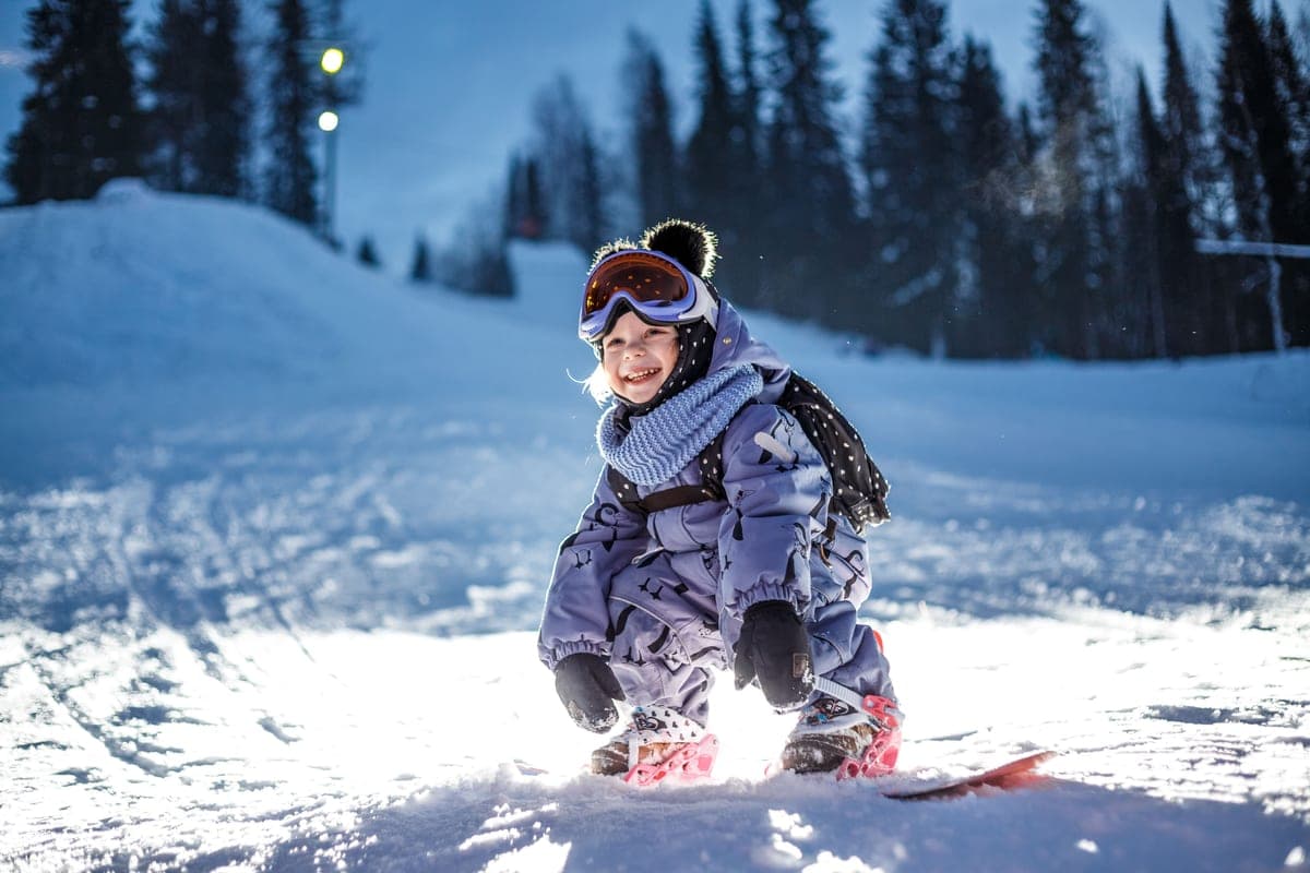 A child snowboarding in a snowy forest in winter