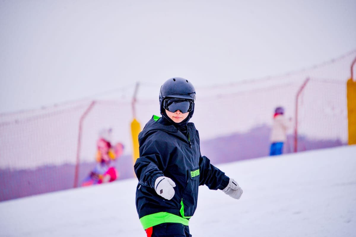 A child skiing on a snow-covered slope in winter gear