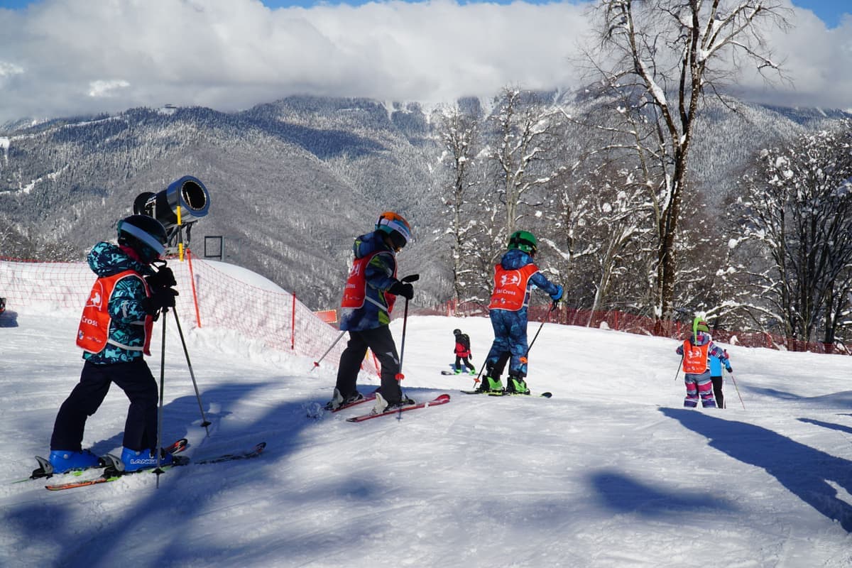 Children learning to ski on a snowy slope under clear winter skies